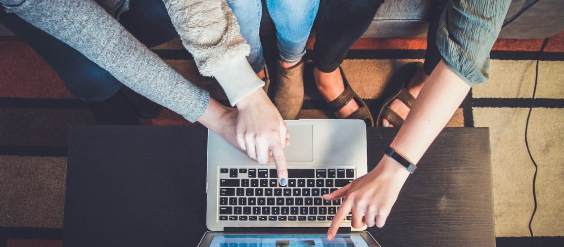 three person pointing the silver laptop computer